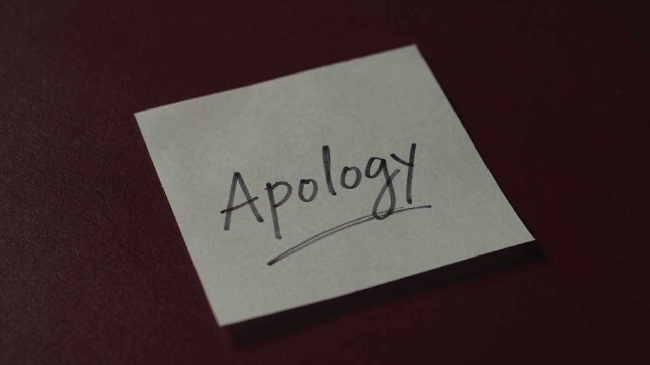 デスクに無造作に置かれた紙切れに走り書きされた謝罪メモ