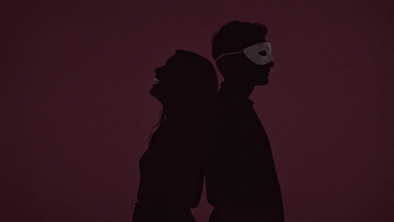 影絵のように並ぶ2人の影が、片方は笑顔でもう片方は仮面をかぶる