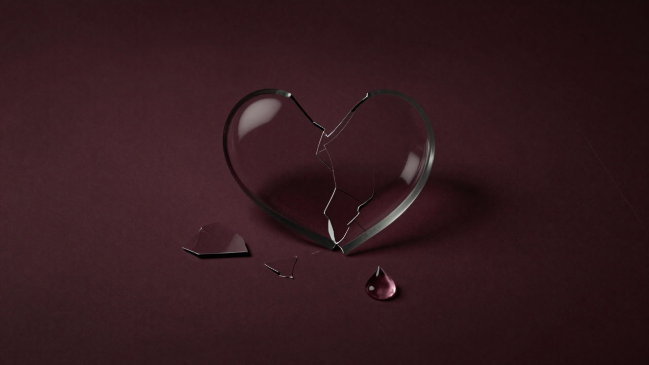 Scattered shards of a broken heart-shaped glass on the floor with a single tear glistening.