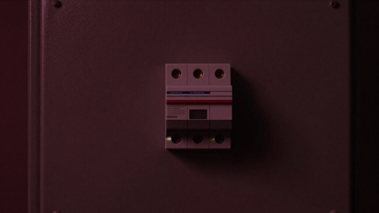 暗い配電盤の中でひそかに光るブレーカーの様子