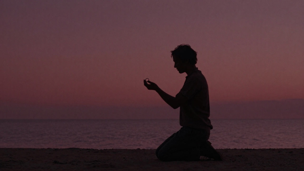 Silhouette of a person offering a ring at sunset by the seaside