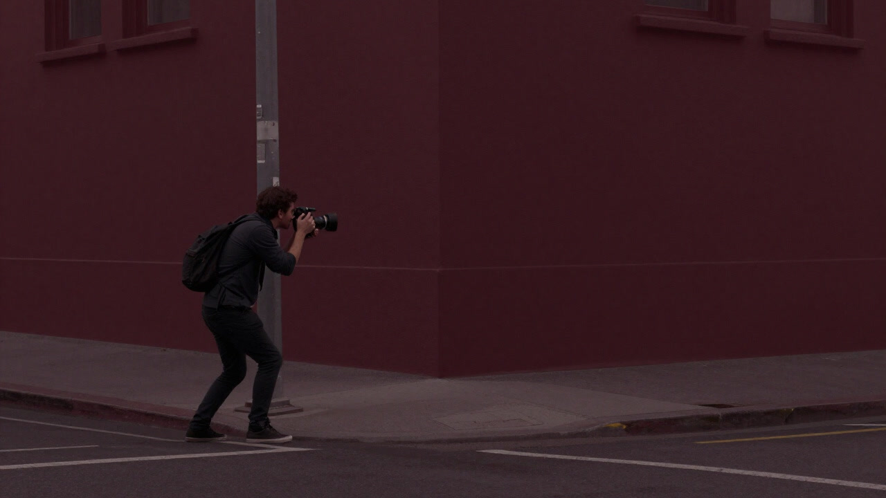A cameraman in a nighttime street corner capturing a distorted reality through the lens.