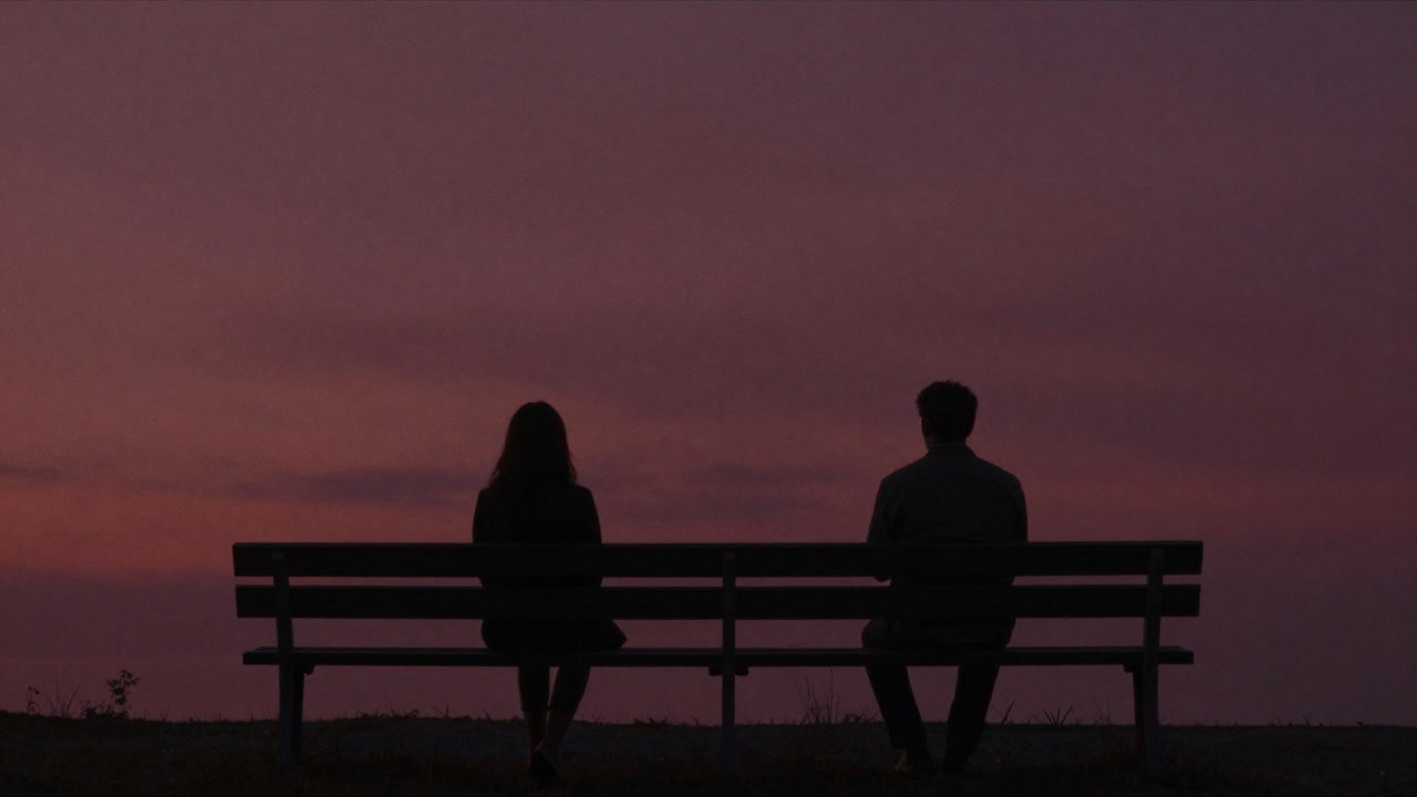 夕焼けのベンチに並んで座る二人の影