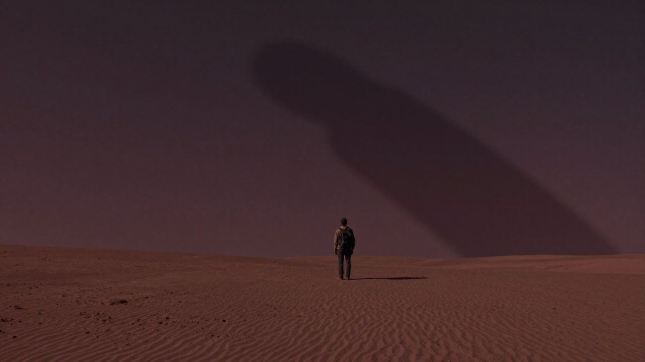 A lone figure standing in a barren landscape, with a giant shadow behind rejecting help.