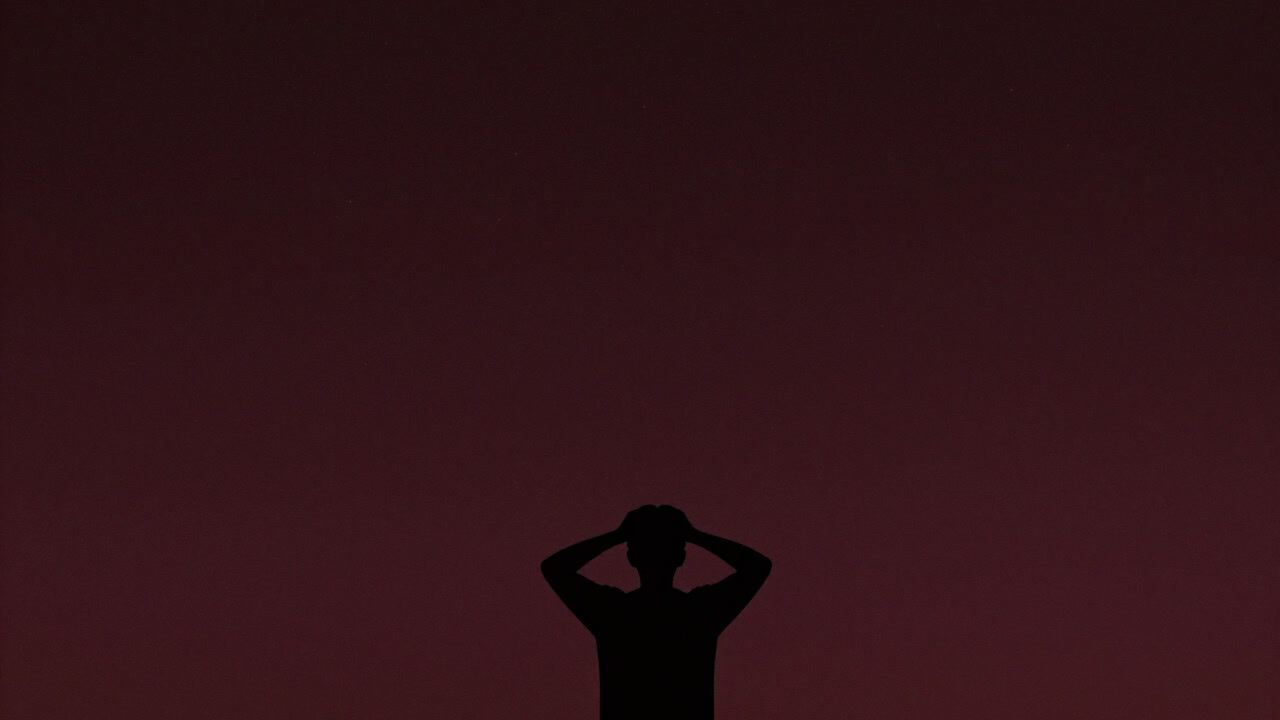 Silhouette of a person holding their head against a starry sky background
