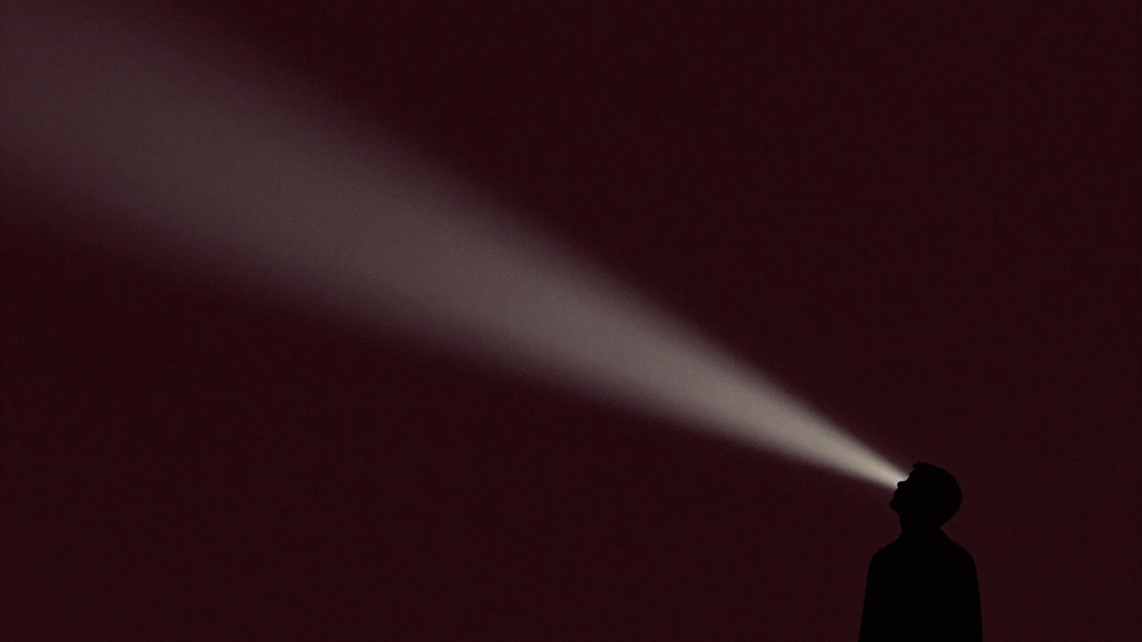 Silhouettes of people gazing at a fading band of light floating in the night sky