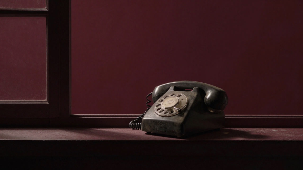 An old rotary phone covered in dust, ringing continuously by a dimly lit window at night