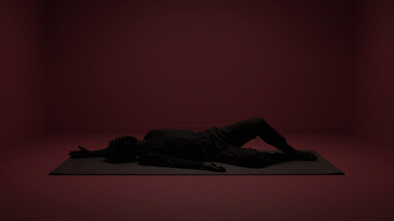 Silhouette of a person twisted into unnatural angles on a soft mat, in visible discomfort