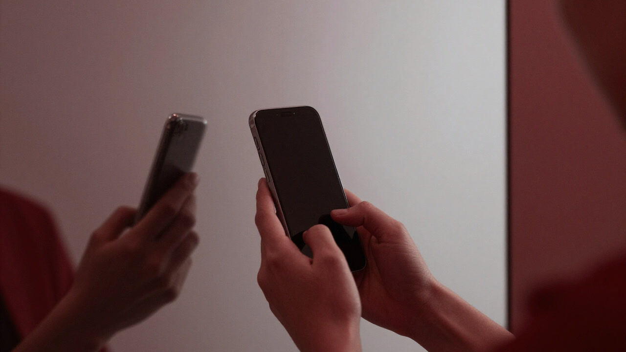 Photo of hands endlessly rubbing a smartphone screen in front of a mirror to make it shine
