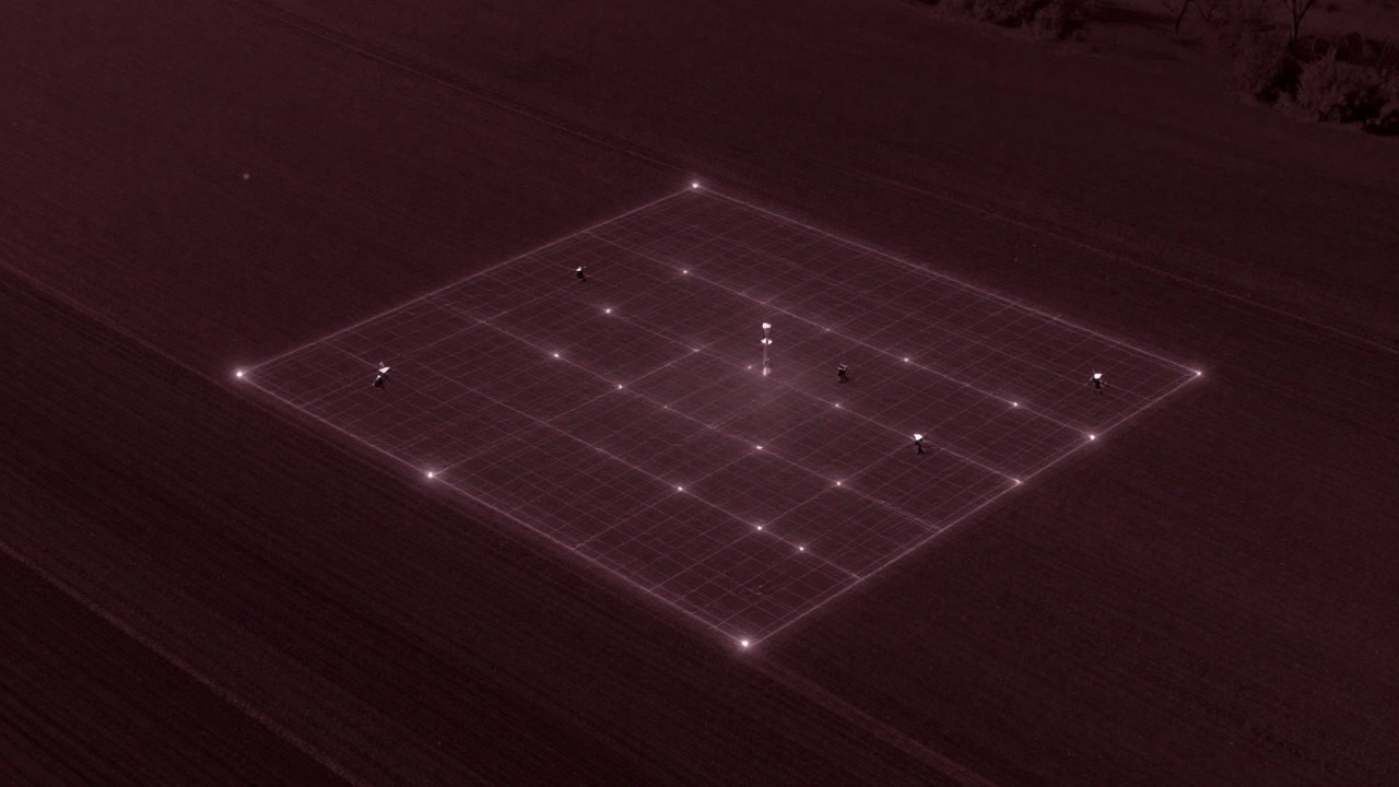 センサーとドローンに囲まれ、デジタルグリッド上で輝く畑の俯瞰図