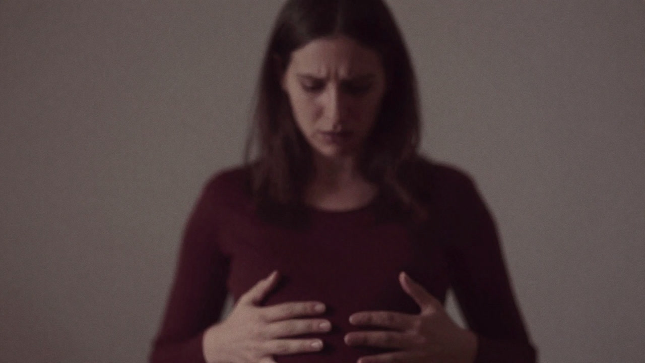 ほんのり膨らんだお腹を優しく抱える手。背景には不安と期待が入り混じった表情のシルエット。