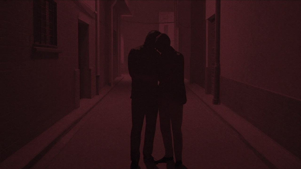 Shadows of two people huddled secretly in a dark alley at night