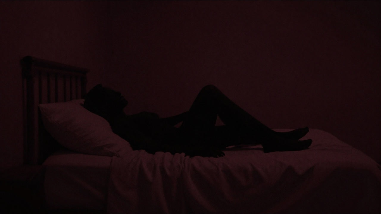 暗い寝室で絡み合うシルエットがぼんやりと浮かぶ画像