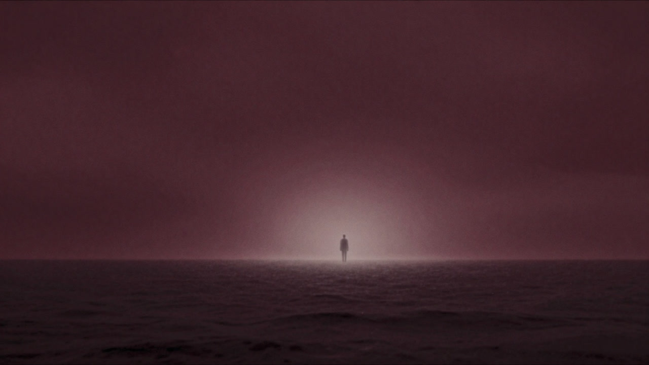 Silhouette of a person standing at the sea-sky boundary bathed in ethereal light, representing a thin place