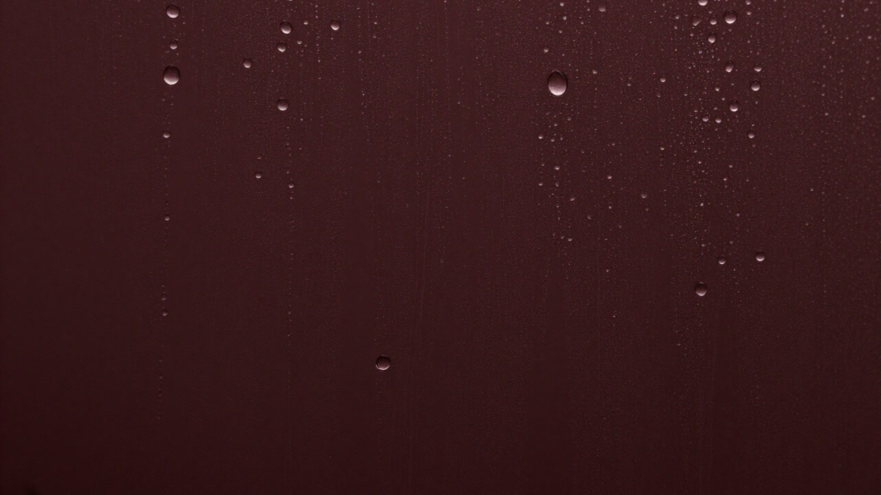 水滴が滑り落ちるガラス面をクローズアップした写真